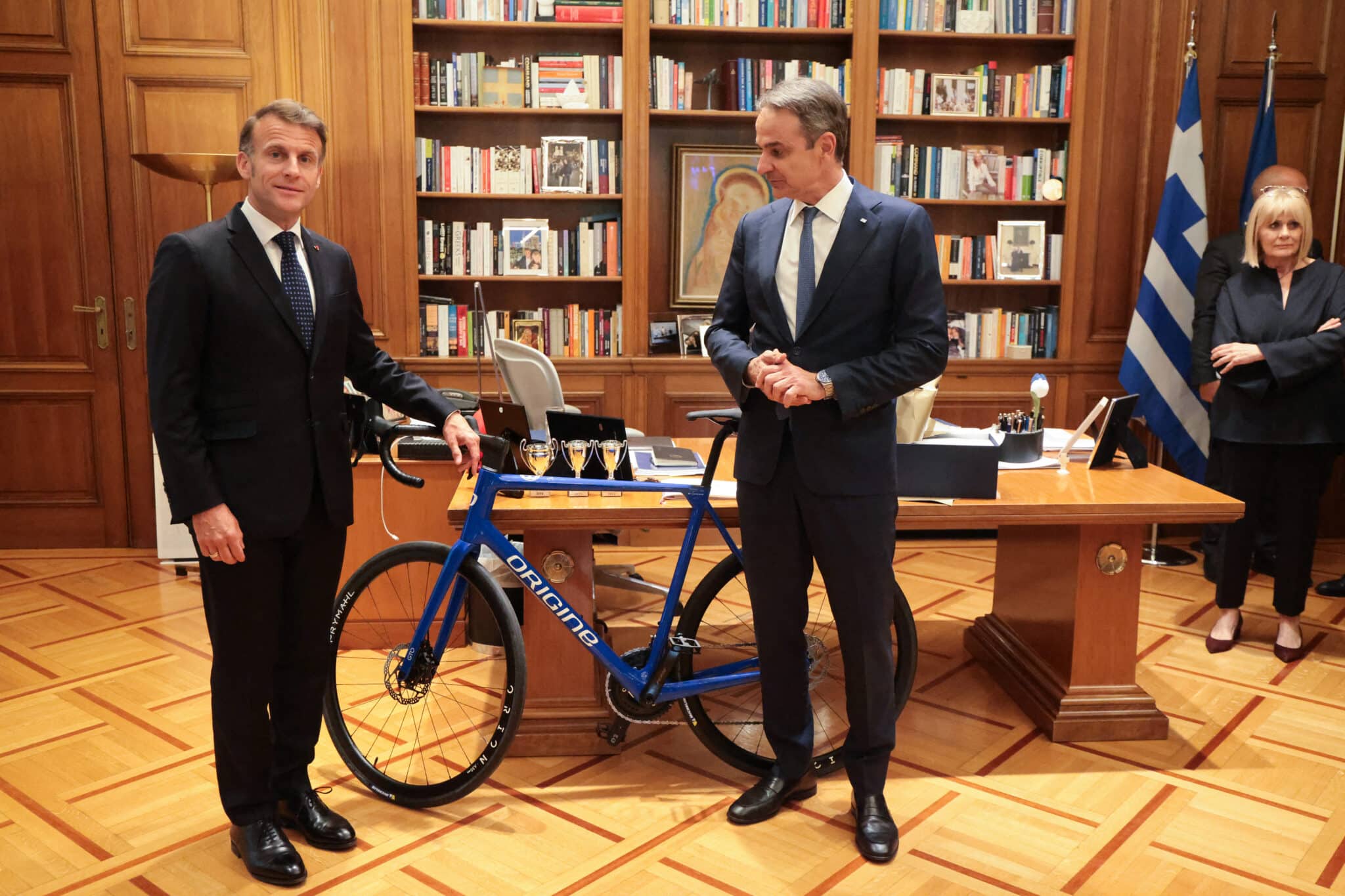 Le Premier ministre grec Kyriakos Mitsotakis (à droite) reçoit des mains du président français Emmanuel Macron un vélo de fabrication française à l'issue d'un déjeuner de travail à Athènes, le 25 avril 2026. Les deux dirigeants ont signé un texte intitulé « Partenariat stratégique global renforcé entre la Grèce et la France » et ont renouvelé l'accord de coopération stratégique en matière de sécurité et de défense. (Photo : Ludovic MARIN / AFP)